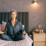 A mature woman practices meditation on her bed, creating a peaceful moment of relaxation, mindfulness, and self-care at home.